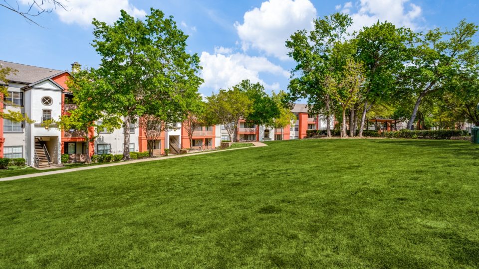the green grass and trees in front of the apartment complex at The  Lana