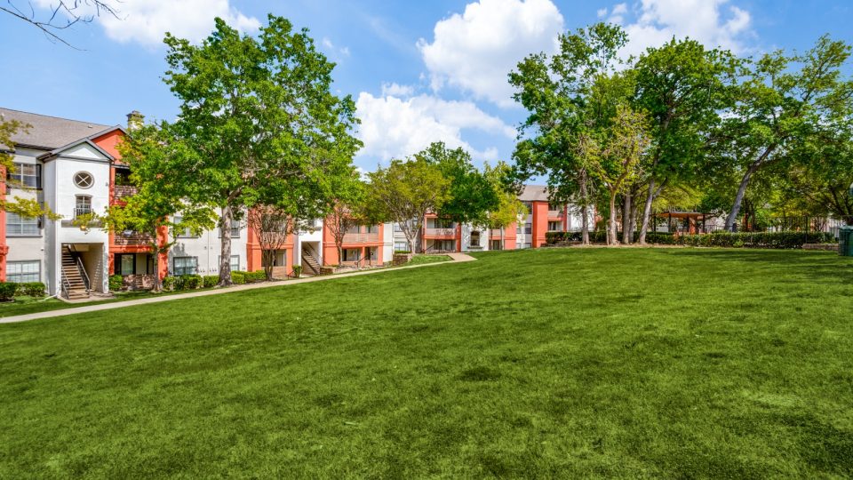 the green grass and trees in front of the apartment complex at The  Lana